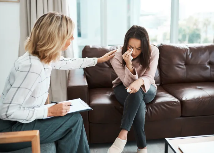 Une femme parle à son thérapeute tout en étant confortablement installée sur un canapé, abordant des sujets personnels